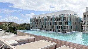 A rooftop pool with a modern building in the background. - Lovely condo w/private pool, 3 min from the beach! (Playa del Carmen)