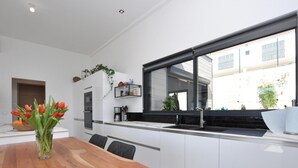 Een moderne keuken met witte kasten, een houten eettafel en een groot raam.