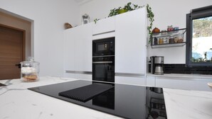 Een moderne keuken met een inbouwoven, een koffiezetapparaat en een plank met potten.