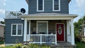 A two-story house with a front porch, a red door, and a satellite dish. - 3bed 2bath nestled in cozy Grandview neighborhood (pet friendly!) (Dubuque)