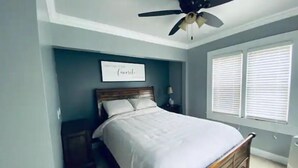 A bedroom with a bed, a ceiling fan, a nightstand, a lamp, and a window with blinds. - 3bed 2bath nestled in cozy Grandview neighborhood (pet friendly!) (Dubuque)