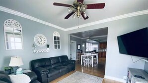A living room with a black leather sofa, a white rug, and a ceiling fan. - 3bed 2bath nestled in cozy Grandview neighborhood (pet friendly!) (Dubuque)