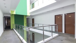 Interior de varios niveles con barandilla de cristal, pared verde y dos puertas con las etiquetas 210 y 211.