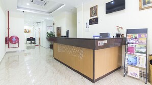 Un área de recepción con un mostrador de madera, un letrero de sala de control de incendios, un televisor y un atril para revistas.