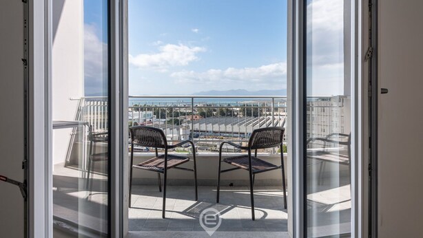 Un balcone con due sedie e vista sulla città e sulle montagne.