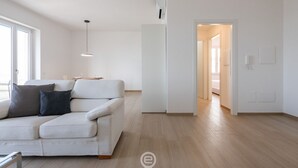 Un soggiorno moderno con un divano bianco, una lampada a sospensione e un pavimento in legno.