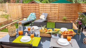 An outdoor dining area with a table set for breakfast, surrounded by wooden fences and greenery. - Le Palmier, mobile home not overlooked (Hyères)
