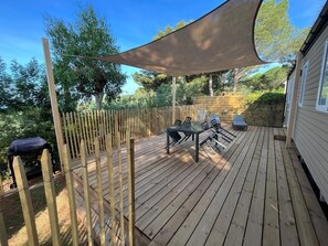 A wooden deck with a table and chairs, surrounded by a bamboo fence and a large shade sail. - Le Cycas, a new mobile home with sea view (Hyères)