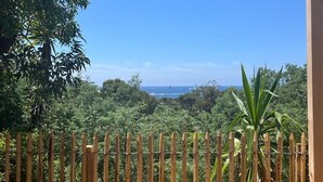 A view through a bamboo fence with a clear sky and distant landscape. - Le Cycas, a new mobile home with sea view (Hyères)