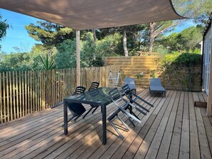An outdoor deck with a table and chairs, surrounded by a wooden fence and trees.