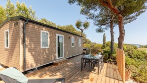 A mobile home with a deck, outdoor seating, and a view of the surrounding landscape. - L'Olivier, mobile home with a sea view (Hyères)