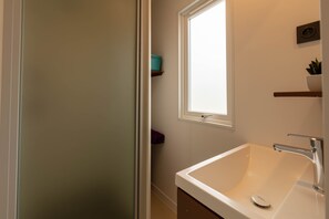 Ein Badezimmer mit einem weißen Waschbecken, einem Fenster und einem Handtuchhalter.