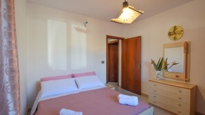 Une chambre à coucher avec un lit, une commode, un miroir et une horloge au mur.