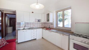 Une cuisine moderne avec des meubles blancs, une cuisinière à gaz et une fenêtre qui laisse entrer la lumière naturelle.