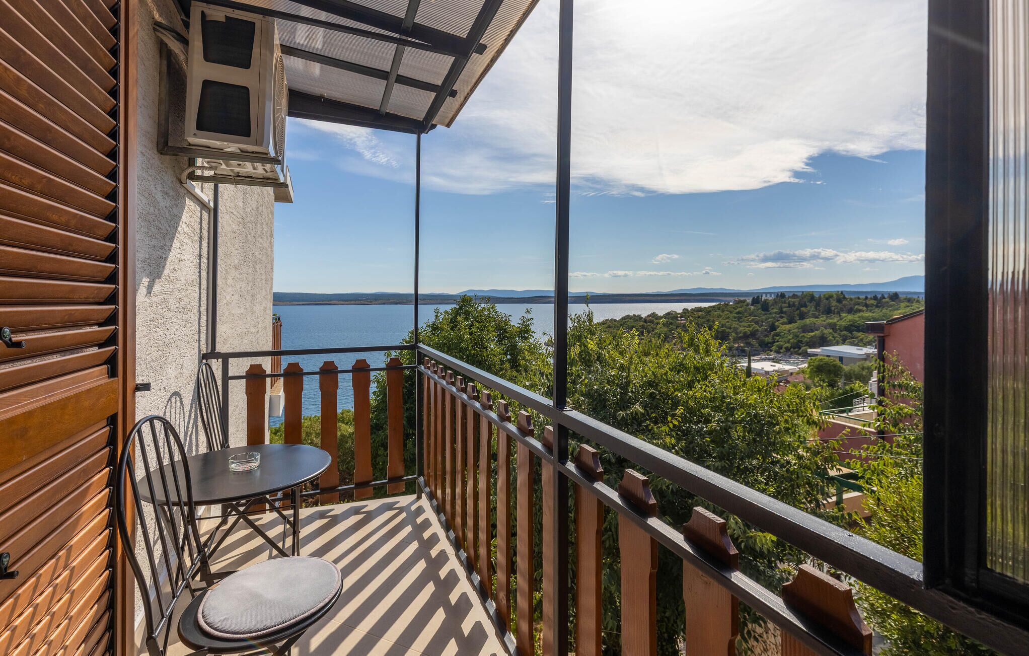 En balkon med udsigt over en sø og fjerne bjerge.