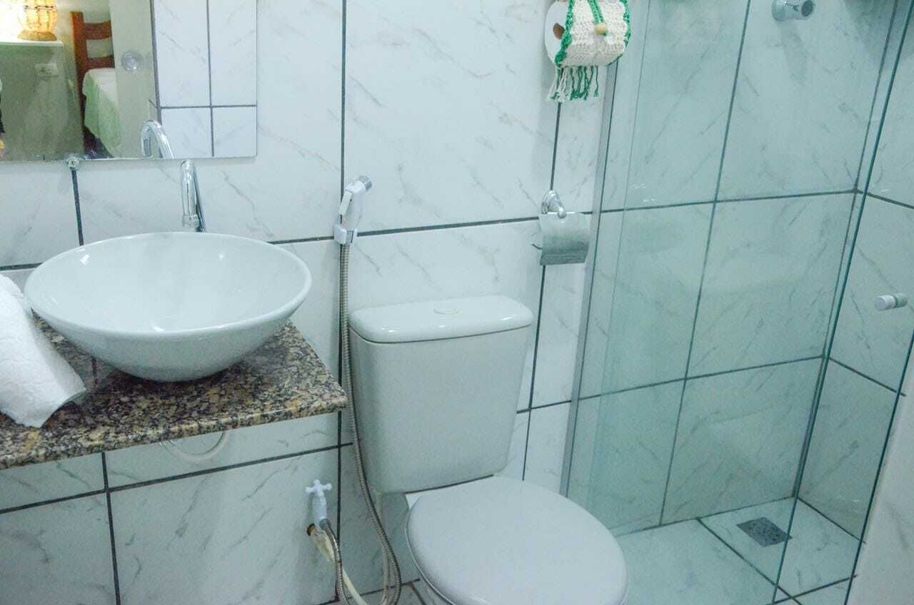 Een badkamer met een wit wastafelmeubel, toilet en douche.