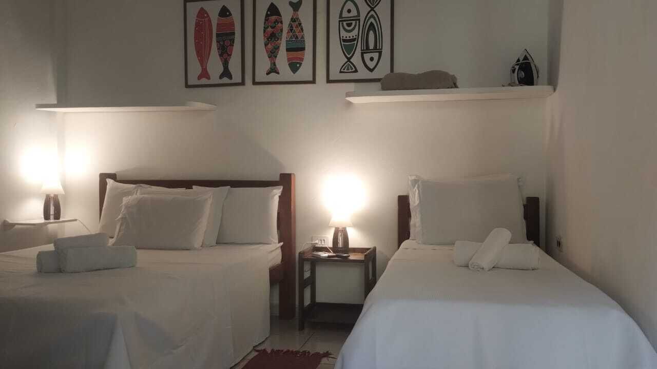 Habitación de hotel con dos camas, una mesita de noche con lámpara y decoración en la pared.