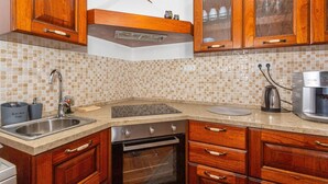 Una cocina con armarios de madera, un lavamanos de acero inoxidable, un horno empotrado y una cafetera.