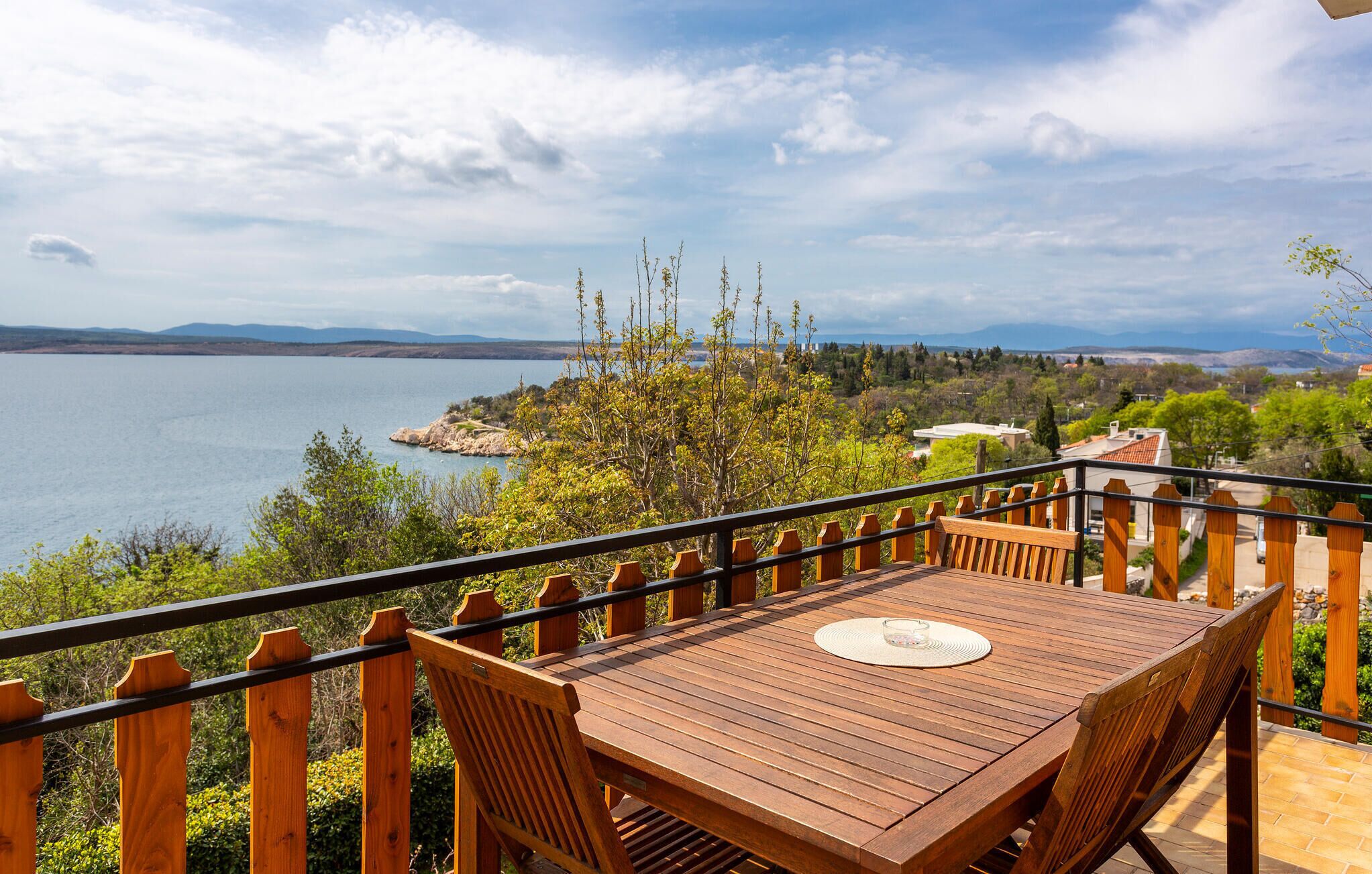 Eine Holzterrasse mit Tisch und Stühlen mit Blick auf einen See.