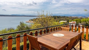 Una terraza de madera con una mesa y sillas, con vista a un lago.