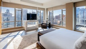 A modern hotel room with large windows, a bed, a desk, and a chair. - Luxurious Penthouse in Trendy Yaletown with Private Rooftop Pool (Vancouver)