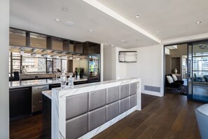 Une cuisine moderne dotée d’un plan de travail en marbre, d’appareils électroménagers intégrés et d’un grand îlot central.