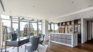 A modern office space with a glass desk, grey chairs, and a city view. - Luxurious Penthouse in Trendy Yaletown with Private Rooftop Pool (Vancouver)