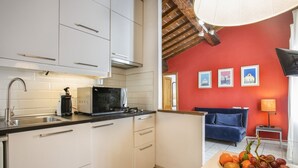 A kitchen with white cabinets, a microwave, and a sink. There is a bowl of fruit on the counter. - Seven House - Sweet Dreams in Florence (Firenze)