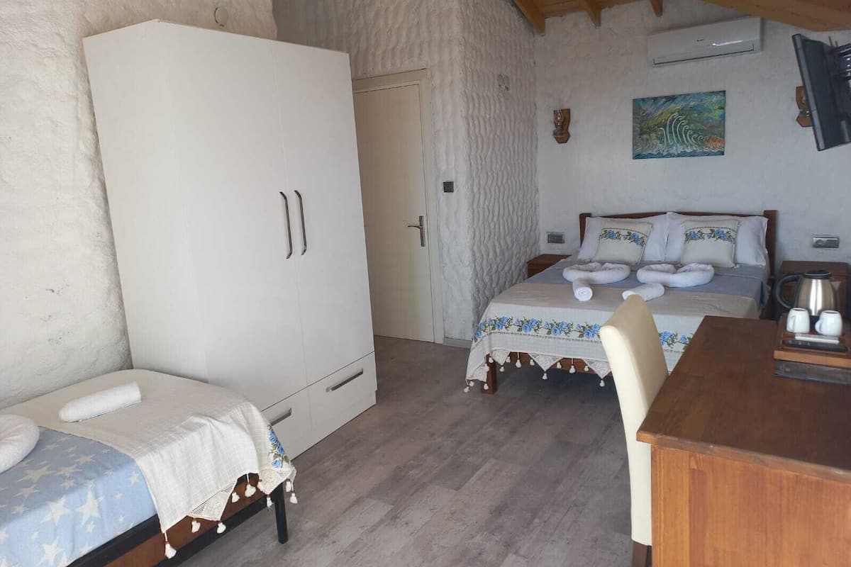 Ein Schlafzimmer mit einem Bett, einem Holztisch, einem Kleiderschrank und einem Bild an der Wand.