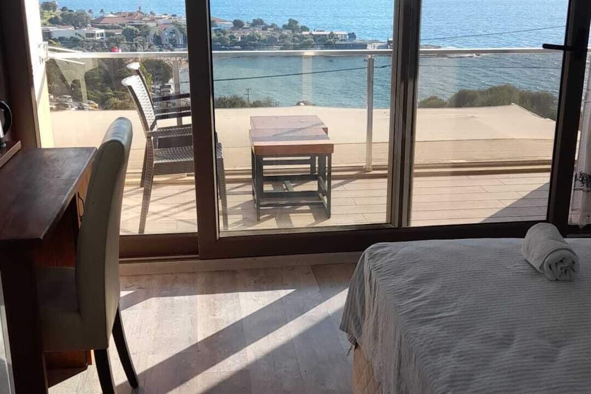 Ein Schlafzimmer mit einer großen Glasschiebetür, die auf einen Balkon mit Meerblick führt.