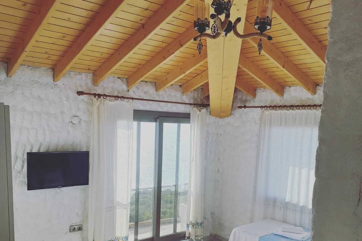 Ein Schlafzimmer mit Holzboden, zwei Betten, einem Fernseher und einem großen Fenster.
