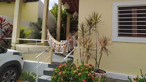 A covered outdoor area with a hammock, steps, and potted plants.