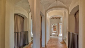 Un couloir orné d’arches, doté d’un sol carrelé et d’une porte donnant sur une pièce.