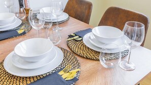 Una mesa de comedor dispuesta con platos blancos, vasos transparentes y un posavasos tejido.