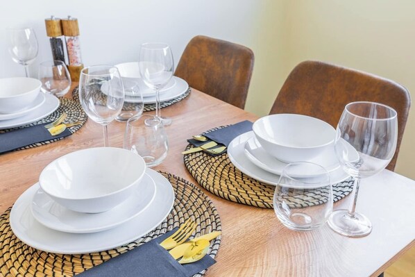 A dining table set with white plates, clear glasses, and a woven placemat.