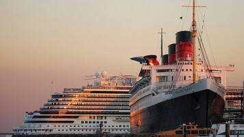 Een groot cruiseschip ligt aangemeerd in een haven, met meerdere dekken en een opvallende schoorsteen.