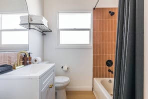 Un baño con un lavamanos blanco, un inodoro, una bañera y una cortina de ducha.