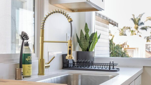 Una cocina moderna con un grifo dorado, una planta en maceta y una botella de EverSpring sobre la encimera.