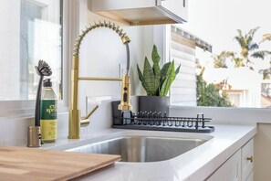 Una cocina moderna con un grifo dorado, una planta en maceta y una botella de EverSpring sobre la encimera.