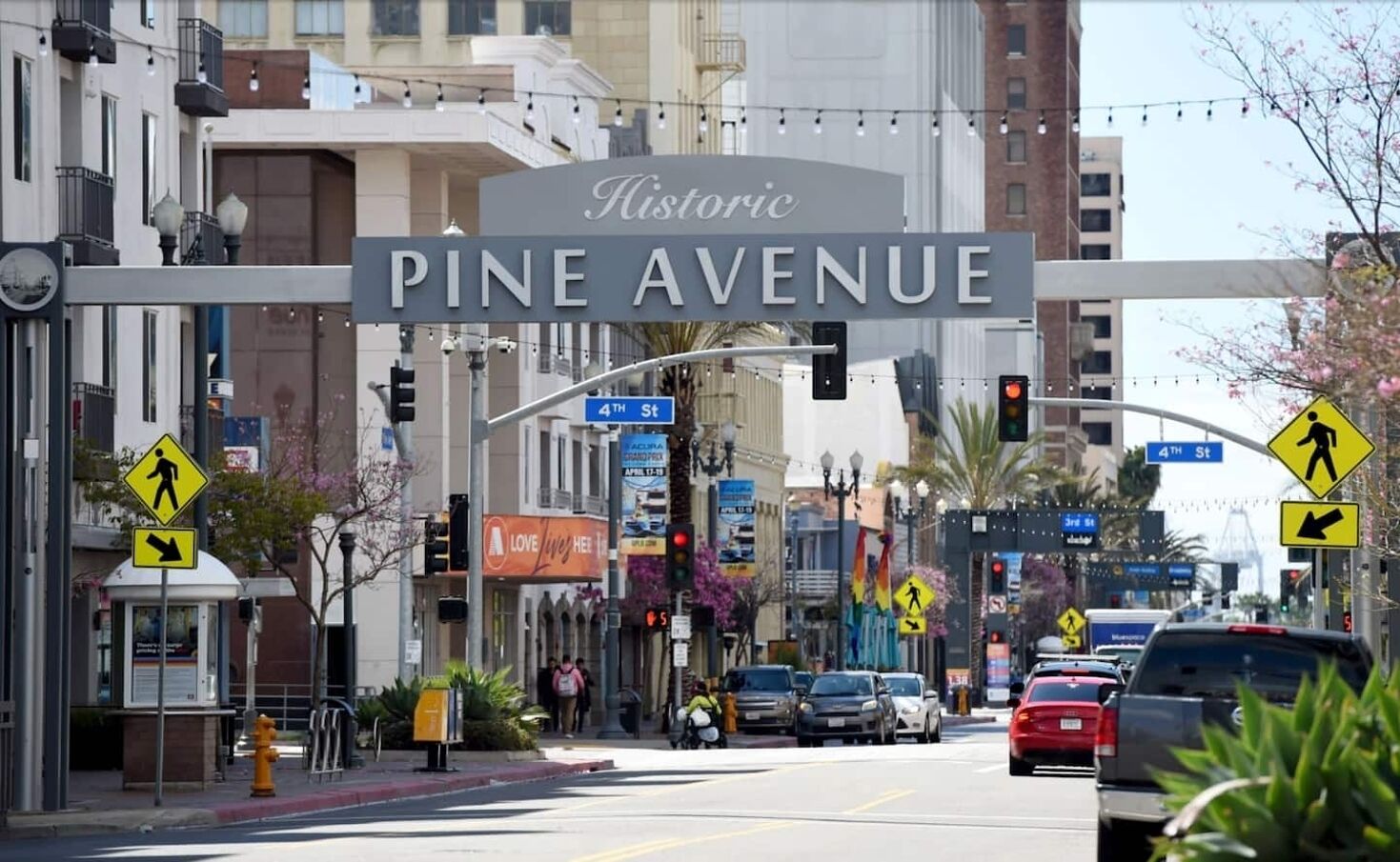 A street sign for Historic Pine Avenue with traffic lights and pedestrian crossing signs.