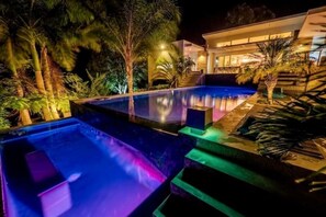 A nighttime view of a modern pool area with a house in the background. - Boutique-style villa with 3-level Cascading Pool (Cabarete)