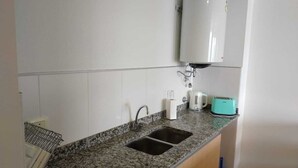 Une cuisine dotée d’un plan de travail en granit, de deux éviers, d’un chauffe-eau blanc, d’un grille-pain et d’un égouttoir à vaisselle.
