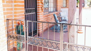 Un edificio de ladrillo con un porche cubierto, una puerta negra y una reja metálica.