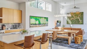 Eine moderne Küche mit Holzschränken, einer großen Kochinsel und einem Essbereich mit Tisch und Stühlen.