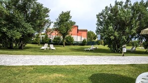 A grassy outdoor area with lounge chairs and a building in the background. - M348 - Marcelli, comfortable new three-room apartment with swimming pool and bal (Numana)