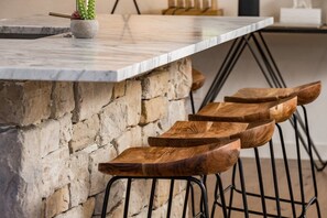 Eine Steinsäule mit einer Holz-Barhocker-Sitzgruppe.