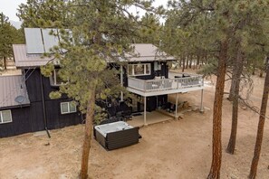 Eine zweistöckige Holzhütte mit Balkon, umgeben von Bäumen.