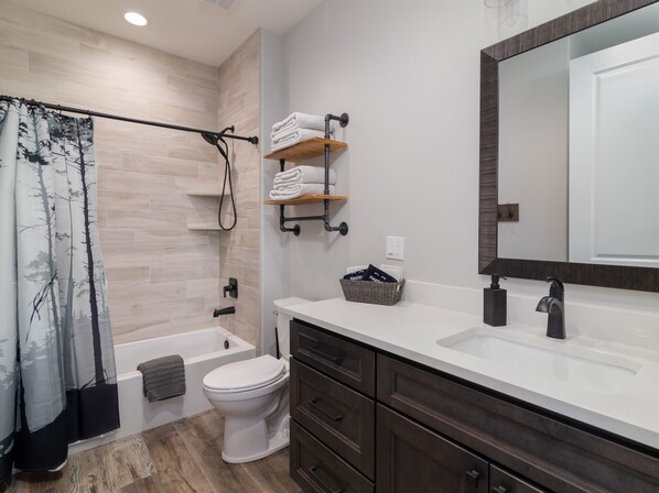 A modern bathroom with a bathtub, toilet, and vanity with a large mirror. - Deer Ridge: Hot Tub, Views, Stargazing, Fire Pit (Orderville)