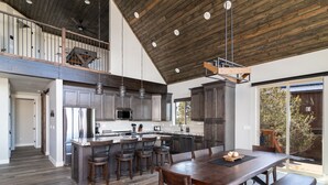 A spacious kitchen with a large island, dark wood flooring, and a high ceiling with exposed beams. - Stargazer Cabin | Private Hot tub | Zion NP (Orderville)