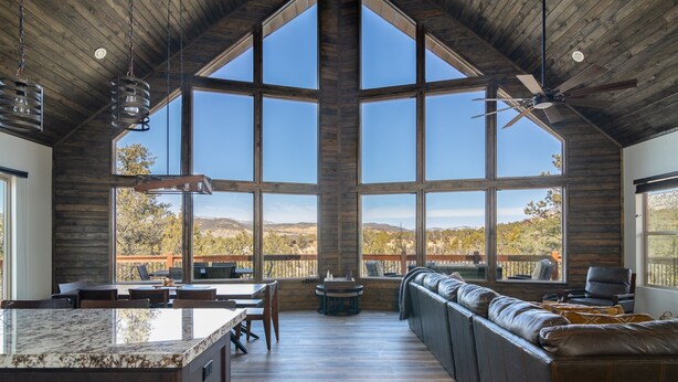 A spacious kitchen with a large island, wooden ceiling, and large windows offering a view of the outdoors. - Stargazer Cabin | Private Hot tub | Zion NP (Orderville)